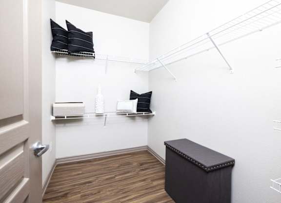 A small room with a bench and a shelf with pillows and boxes on it.