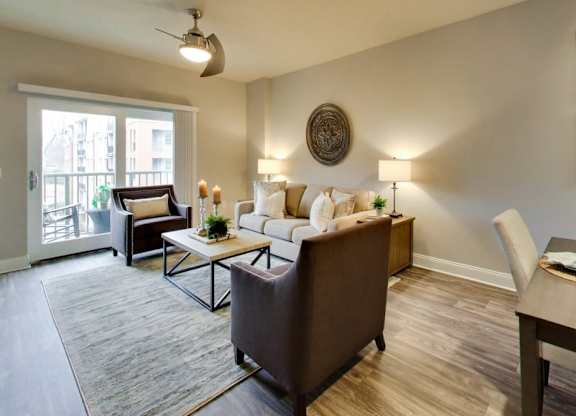A living room with a brown couch, a coffee table, and a dining table with chairs.