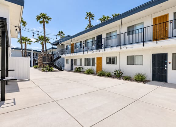 A sunny day at a white building with black railings and yellow doors.