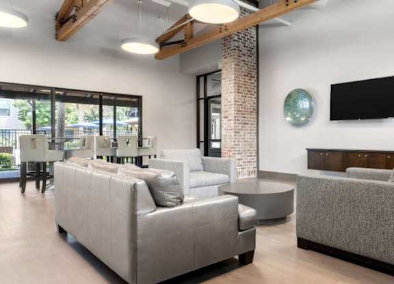 A living room with a grey couch and a flat screen TV mounted on the wall.