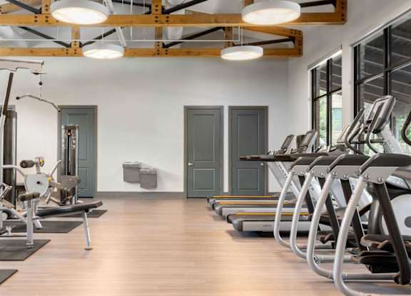 A gym with a variety of equipment including treadmills, weights, and exercise machines.