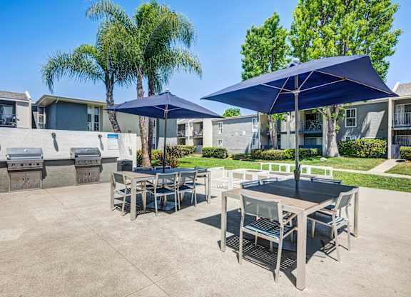 A patio with a table and chairs under umbrellas.