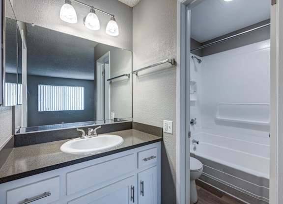 A bathroom with a sink, mirror, and shower.