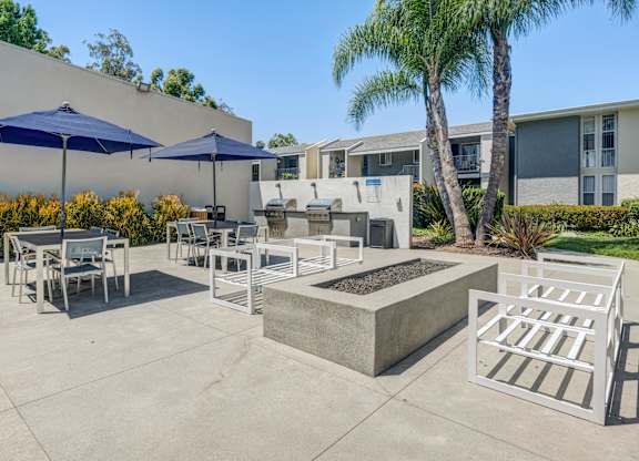 A patio with a table, chairs, and umbrellas.