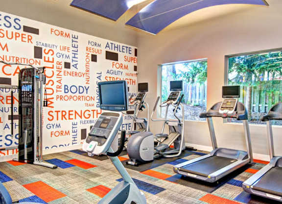 A gym with a variety of equipment including treadmills, stationary bikes, and weight machines.