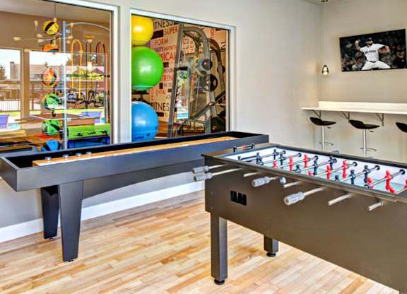 A room with a foosball table and a pool table.
