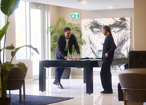 Two people are standing in a room with a large painting on the wall and a green exit sign above them at The Dale Apartments , Ottawa, Ontario