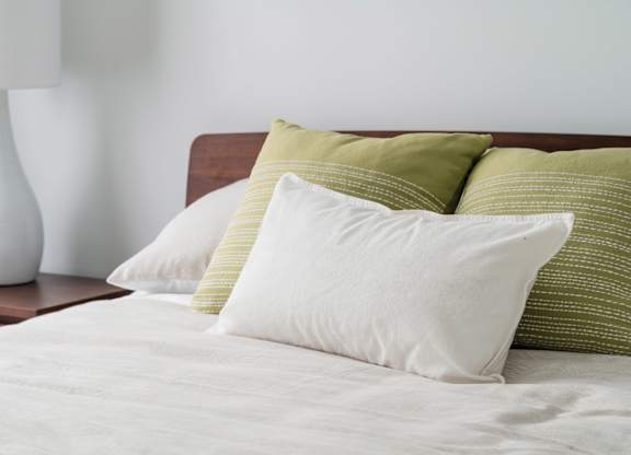 Bedroom with white linens and green pillows at Kanata Lakes Apartments, Ottawa, K2T 0K3