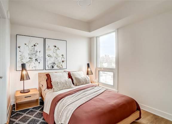 Modern bedroom with corner windows and artwork at Baseline Apartments, Ottawa, K2H 0C9