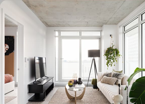 A living room with a white couch, a black coffee table, and a large window.