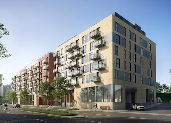 A modern apartment building with balconies on the upper floors.