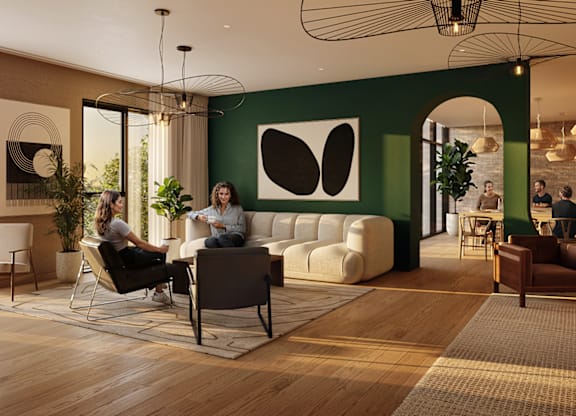 Two people sitting in a room with a green wall and a large black and white painting.