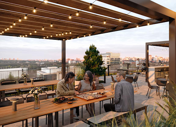 People are sitting at a wooden table under a pergola with string lights.