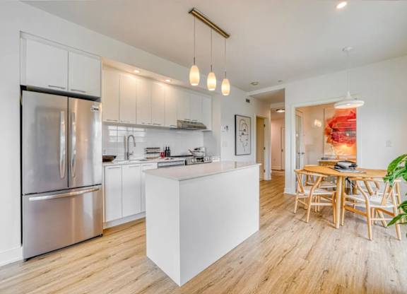 A modern kitchen with a wooden floor and white cabinets. at Château golf, Gatineau, J9H 0M9