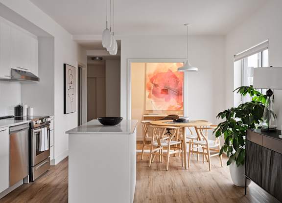 A modern kitchen with a white island and wooden chairs. at Château golf, Gatineau Quebec