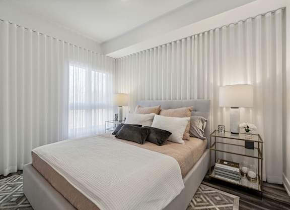 Modern bedroom with neutral bedding and curtains at Horizon Apartments, Quebec, J9A 0G9