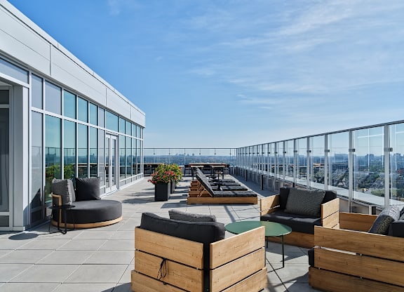 A rooftop patio with wooden furniture and a glass railing. at Le ColumbiaApartments , Gatineau, QC