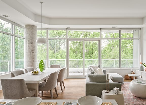 A modern dining room with a table set for two and a view of the trees outside at Petries Landing I Apartments , Ottawa, ON
