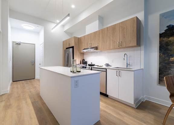 Modern kitchen with white island and wood cabinets at Petries Landing II Apartments, Ottawa