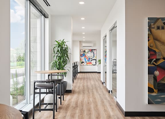 A long hallway with a table and chairs on the left and a painting on the right.