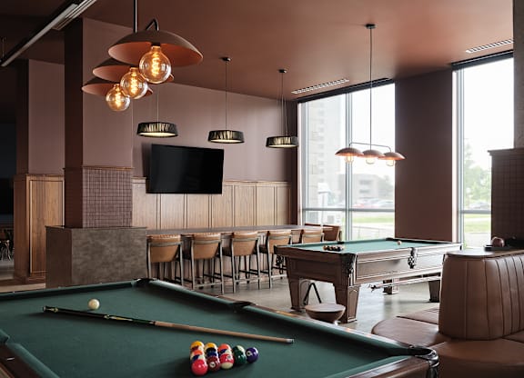 A pool table with a green felt cloth and a television mounted on the wall at The Dale Apartments , Ontario, K1Y 4Y5