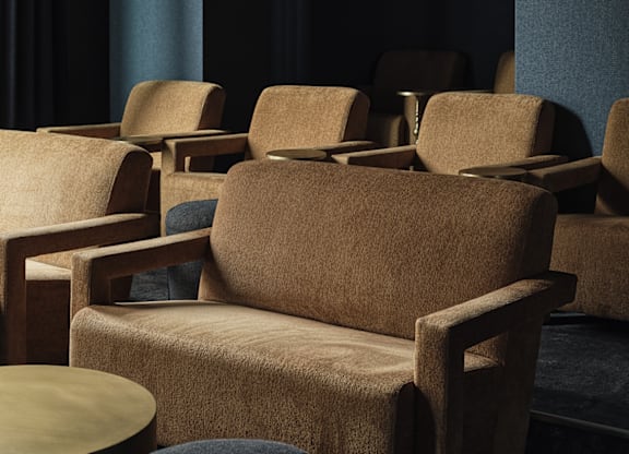 A set of brown chairs and a table are arranged in a waiting area.