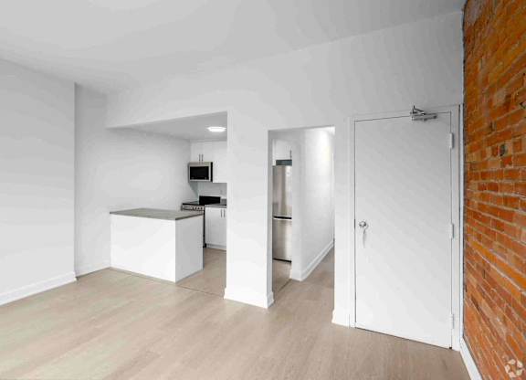 A kitchen area with a white counter and a refrigerator.