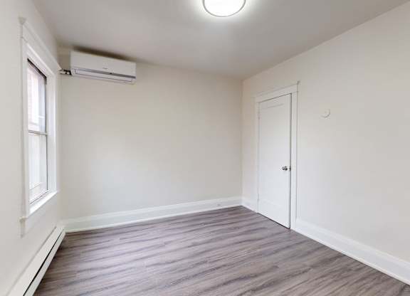 A room with a window and a door is empty and waiting to be furnished.