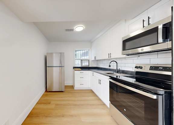 A kitchen with white cabinets and black appliances.