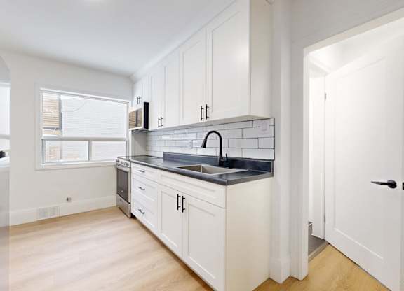 A kitchen with white cabinets and a black countertop.
