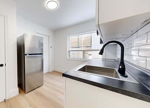 A kitchen with a sink, refrigerator, and a window.