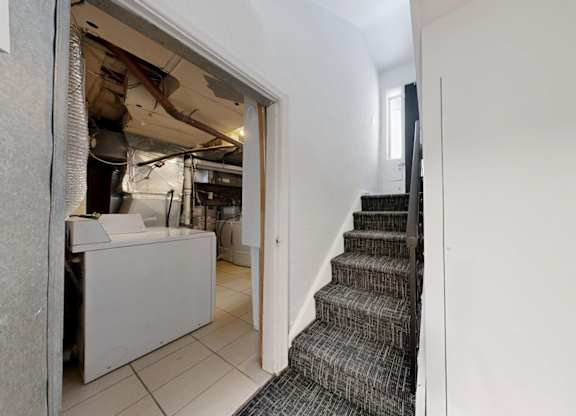 A staircase with a carpeted runner leads up to a doorway.