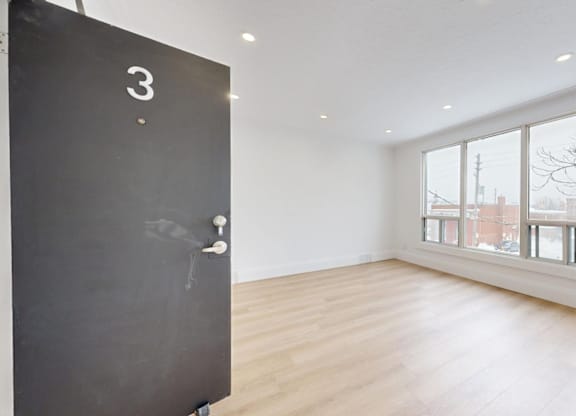 A black door with the number 3 on it is in a room with a large window.
