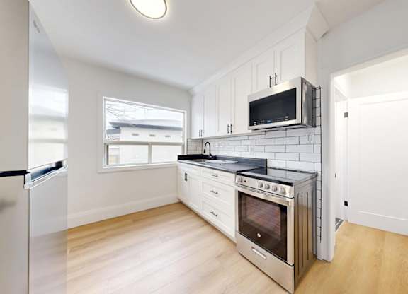 A kitchen with a refrigerator, oven, and microwave.