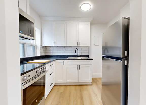 A kitchen with white cabinets and a black countertop.