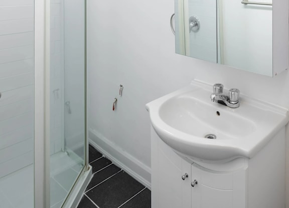 A white sink in a bathroom with a glass shower door.
