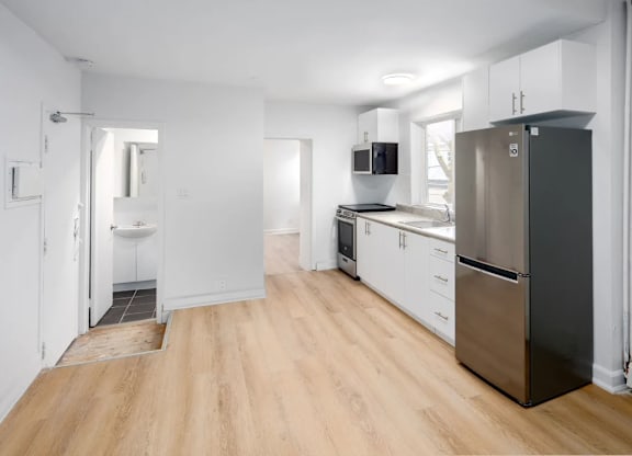 A kitchen with a refrigerator, sink, and cabinets.