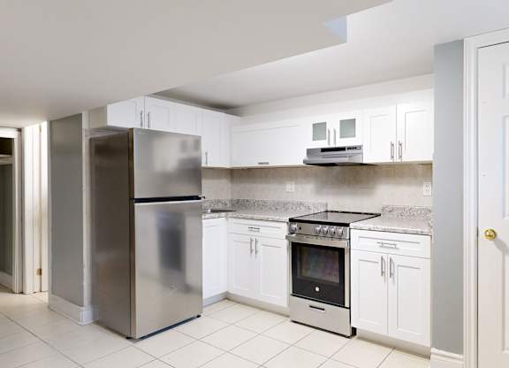 A kitchen with white cabinets and a stainless steel refrigerator.