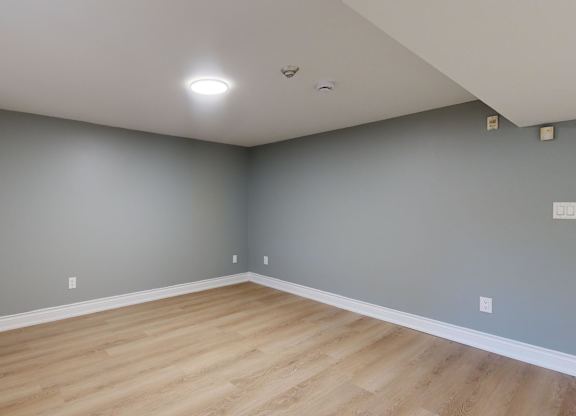 A room with wooden flooring and grey walls.