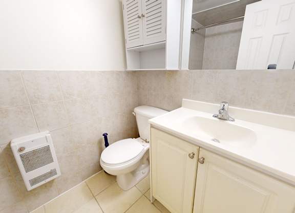 A bathroom with a toilet, sink, and cabinet.