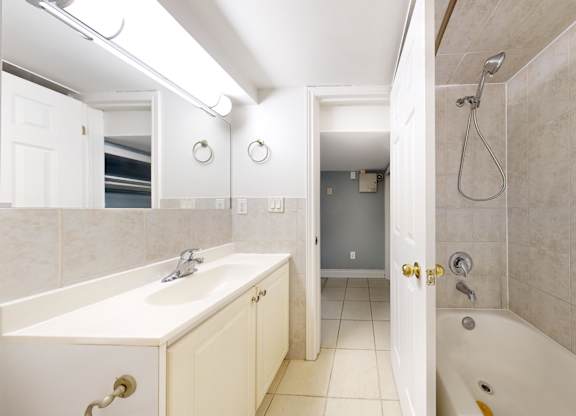 A white bathroom with a sink, mirror, and bathtub.