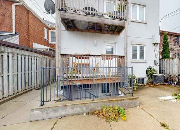 A patio with a table and chairs is surrounded by a fence and a bicycle is parked in the yard.
