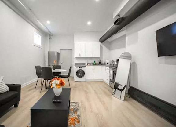 A black sofa sits in a living room with a dining table and chairs.