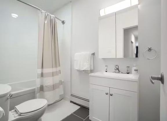 A white bathroom with a toilet, sink, and shower.