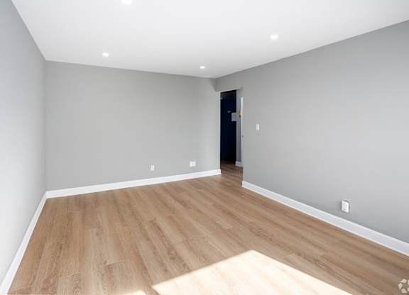 A room with wooden flooring and a door in the background.
