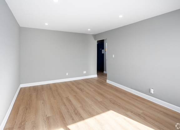 A room with wooden flooring and a door in the background.