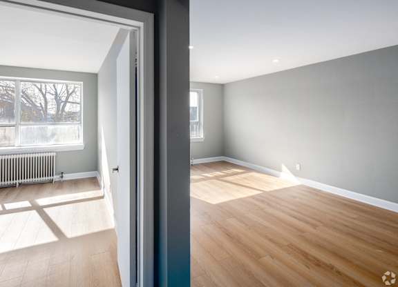 A room with wooden flooring and a grey wall.