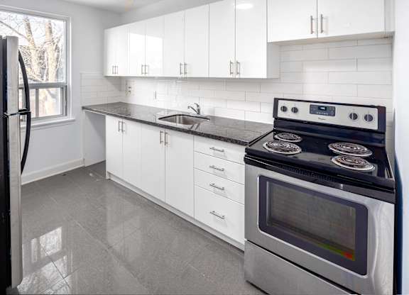 A modern kitchen with a black stove top oven and white cabinets.