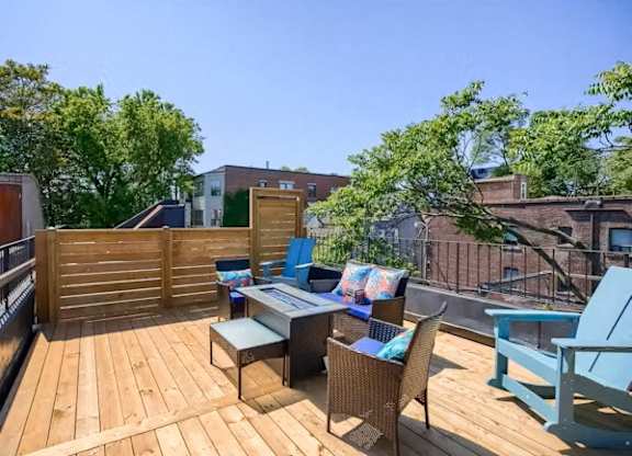 A wooden deck with a table and chairs is surrounded by trees.