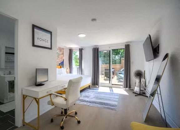 A room with a desk, chair, and a framed picture on the wall.